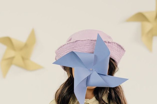 selective focus of a girl covering her face with pinwheel