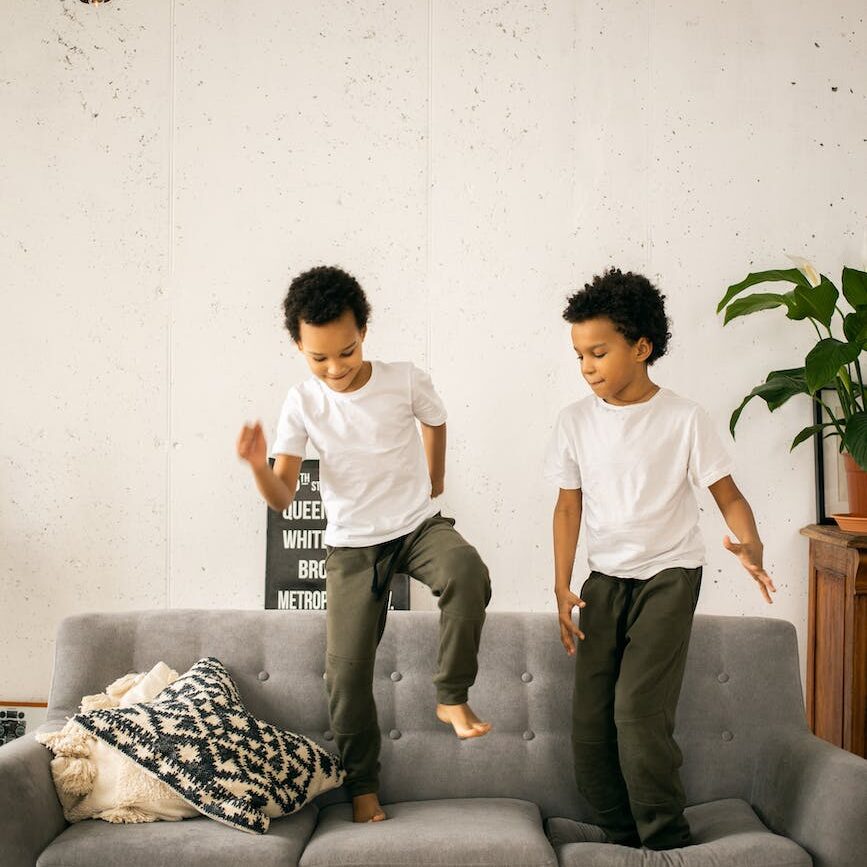 black brothers standing on sofa in living room