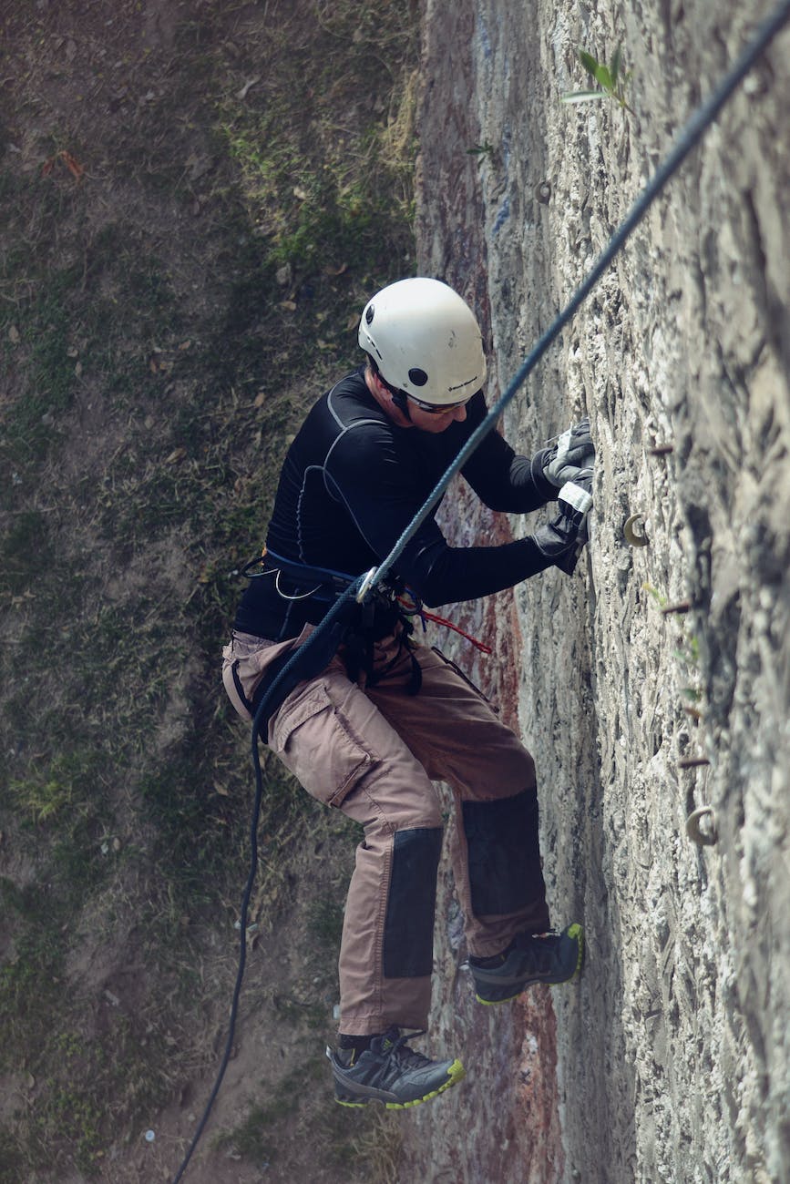 person in white hard hat climbing wall