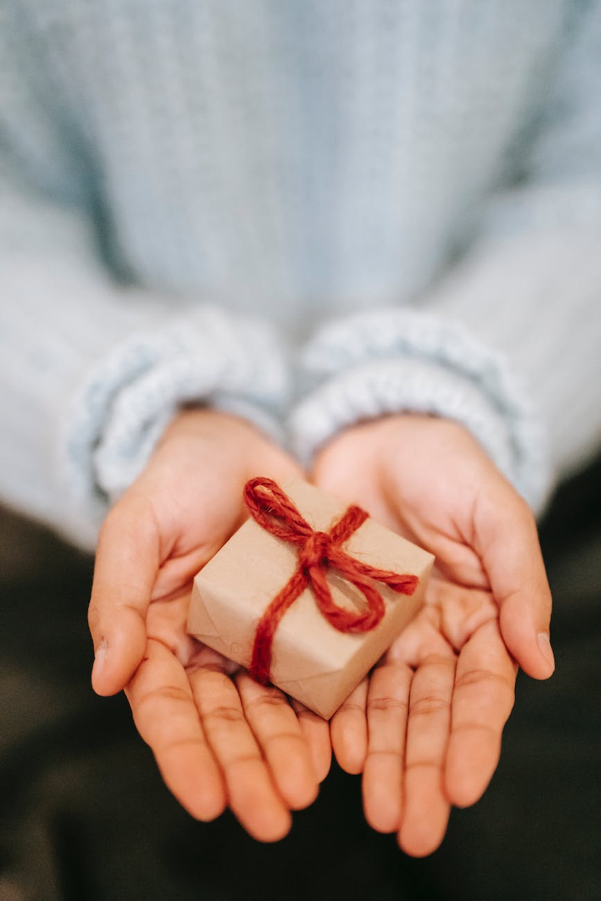 crop faceless woman showing small gift box on palms